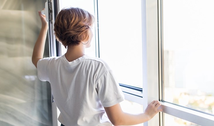 Eine Frau oeffnet ein Fenster