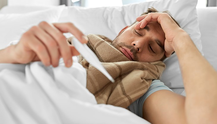 Ein Mann liegt mit Fieber im Bett