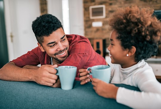Vater und Tochter schauen sich an und trinken Tee